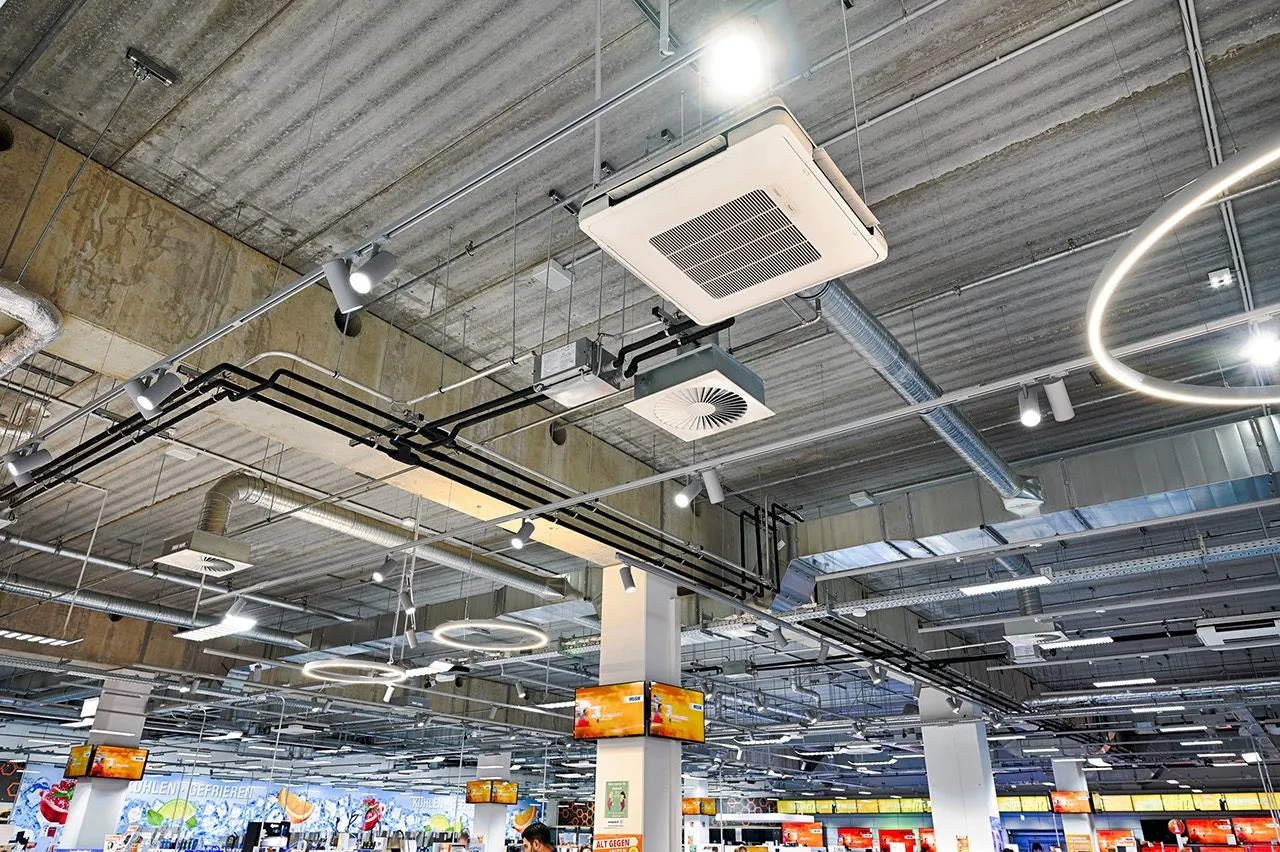 Unités de climatisation en cassette et réseau de gaines sous le plafond d'un supermarché