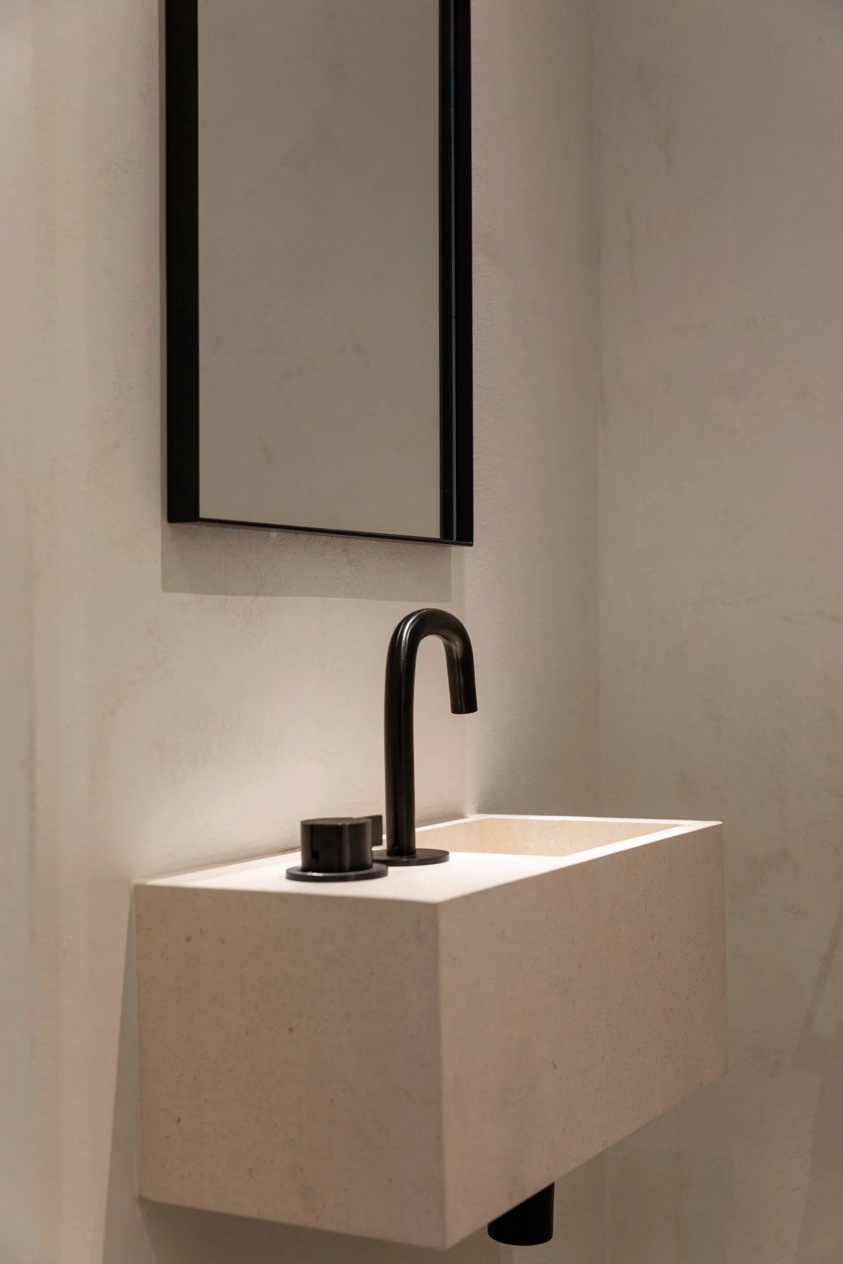Lavabo en pierre et robinetterie noire dans une salle de bain réalisée par Hydroline
